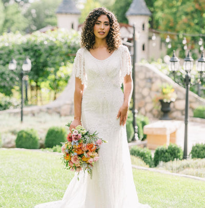 Bride wearing a pearl beaded modest wedding dress with flutter sleeves and a scoop neckline