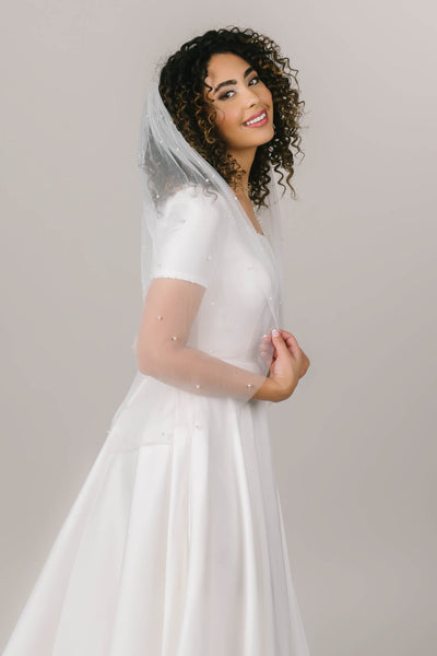 This is a side shot of a bride wearing a finger tip length pearl veil.