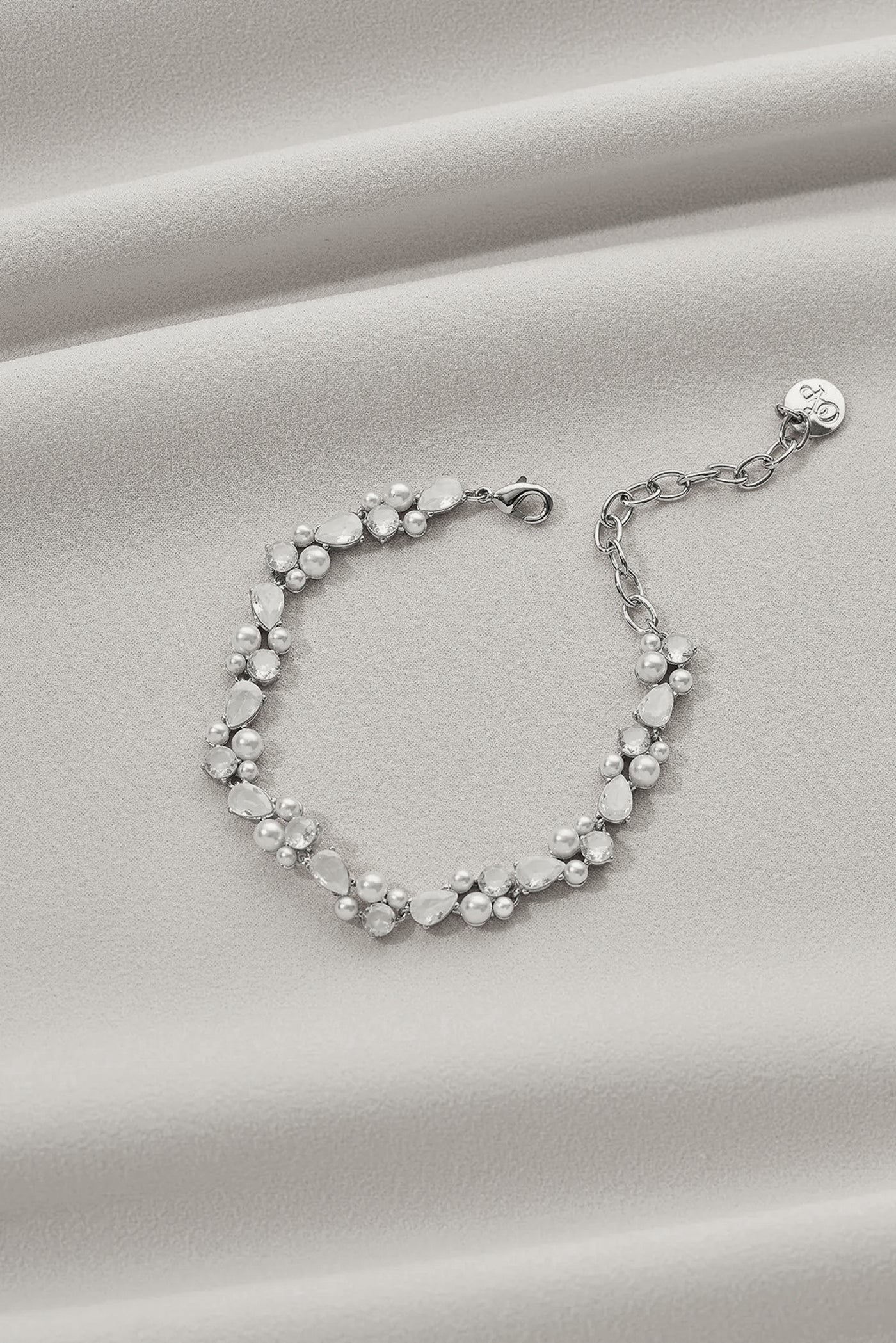 A silver bracelet with teardrop gems and little pearl details.