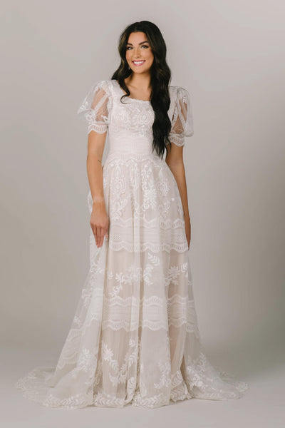 This is a front shot of a modest wedding dress with lacy details and an a-line silhouette.
