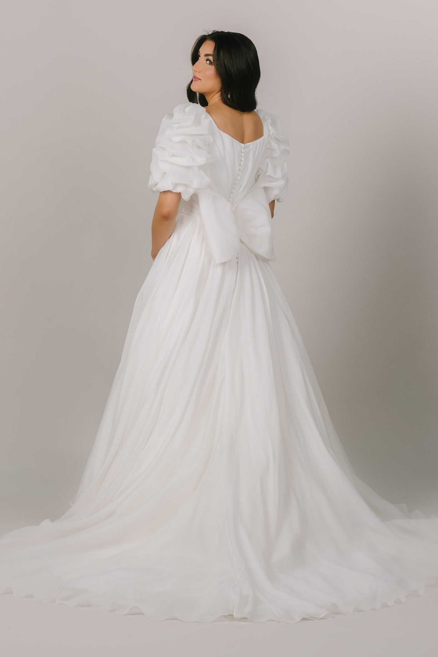 This is a back shot of a modest wedding dress with a large bow on the back and a fun sleeve option.