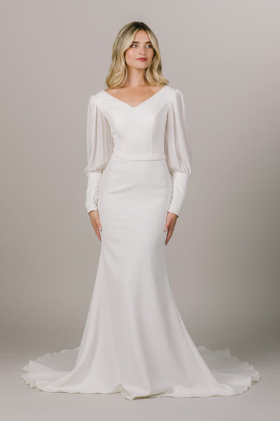 This is a front shot of a modest wedding dress with sheer chiffon sleeves and defined waistband.
