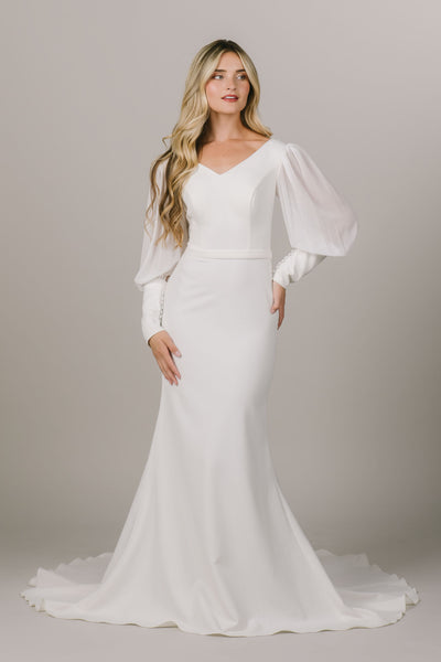 This is a front shot of a modest wedding dress with a v-neckline and sheer chiffon sleeves.