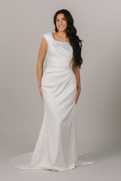 This is a front shot of a modest wedding dress with a square neckline and ruched bodice.