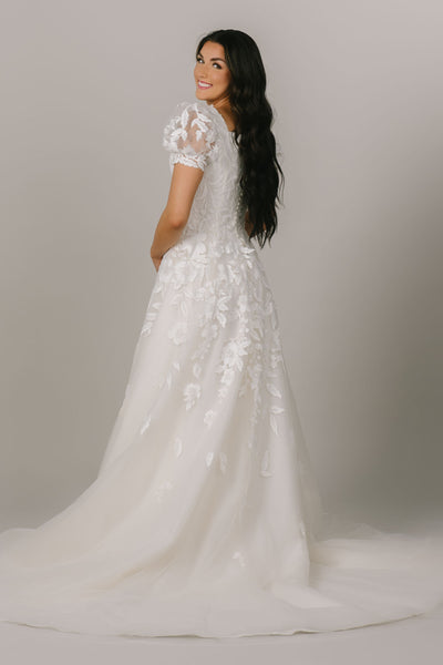 This is a back shot of a modest wedding dress with puff sleeves, a-line silhouette, and floral applique.