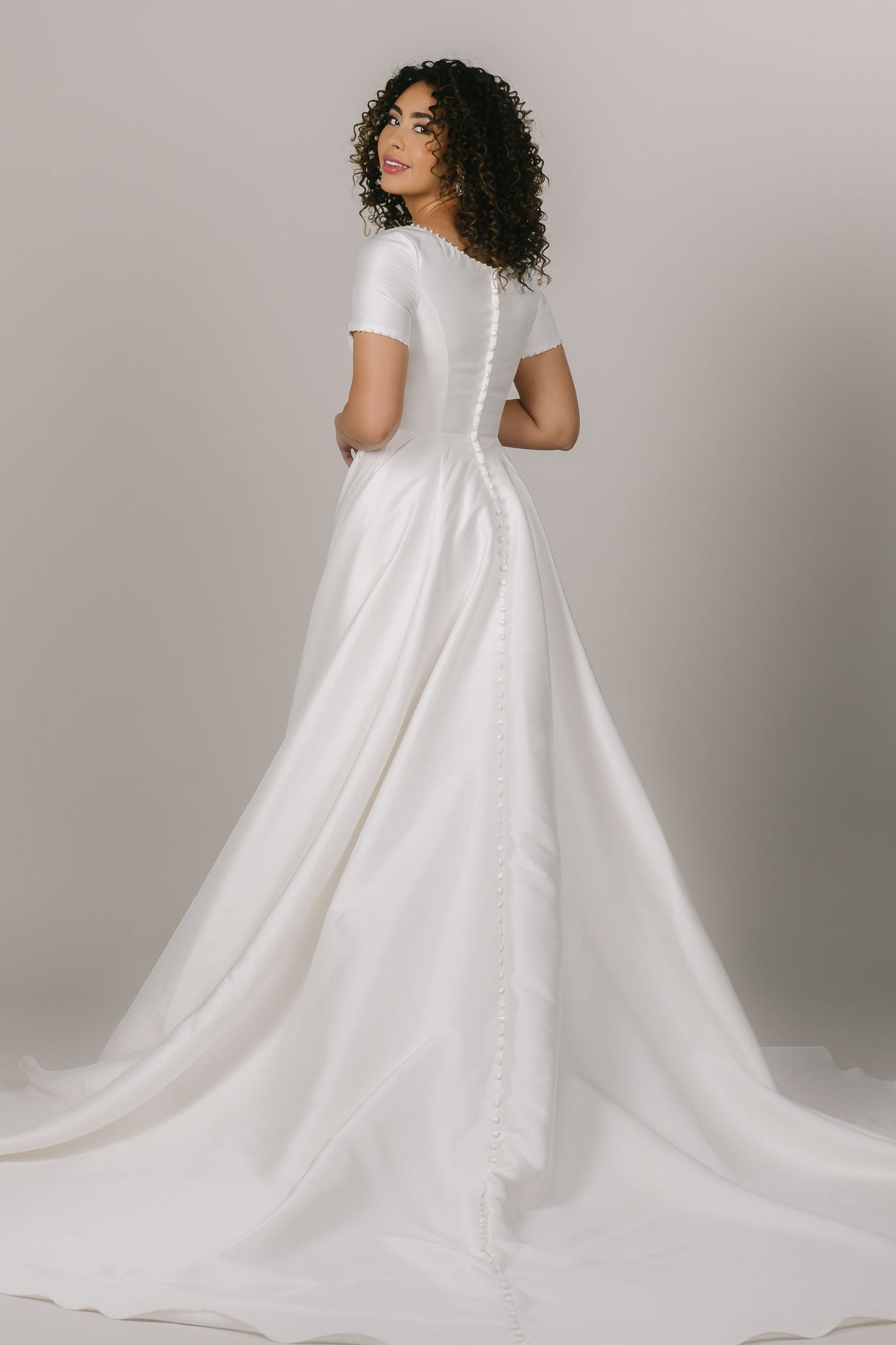 This is a back shot of a modest wedding dress with an a-line silhouette and buttons all down the back.