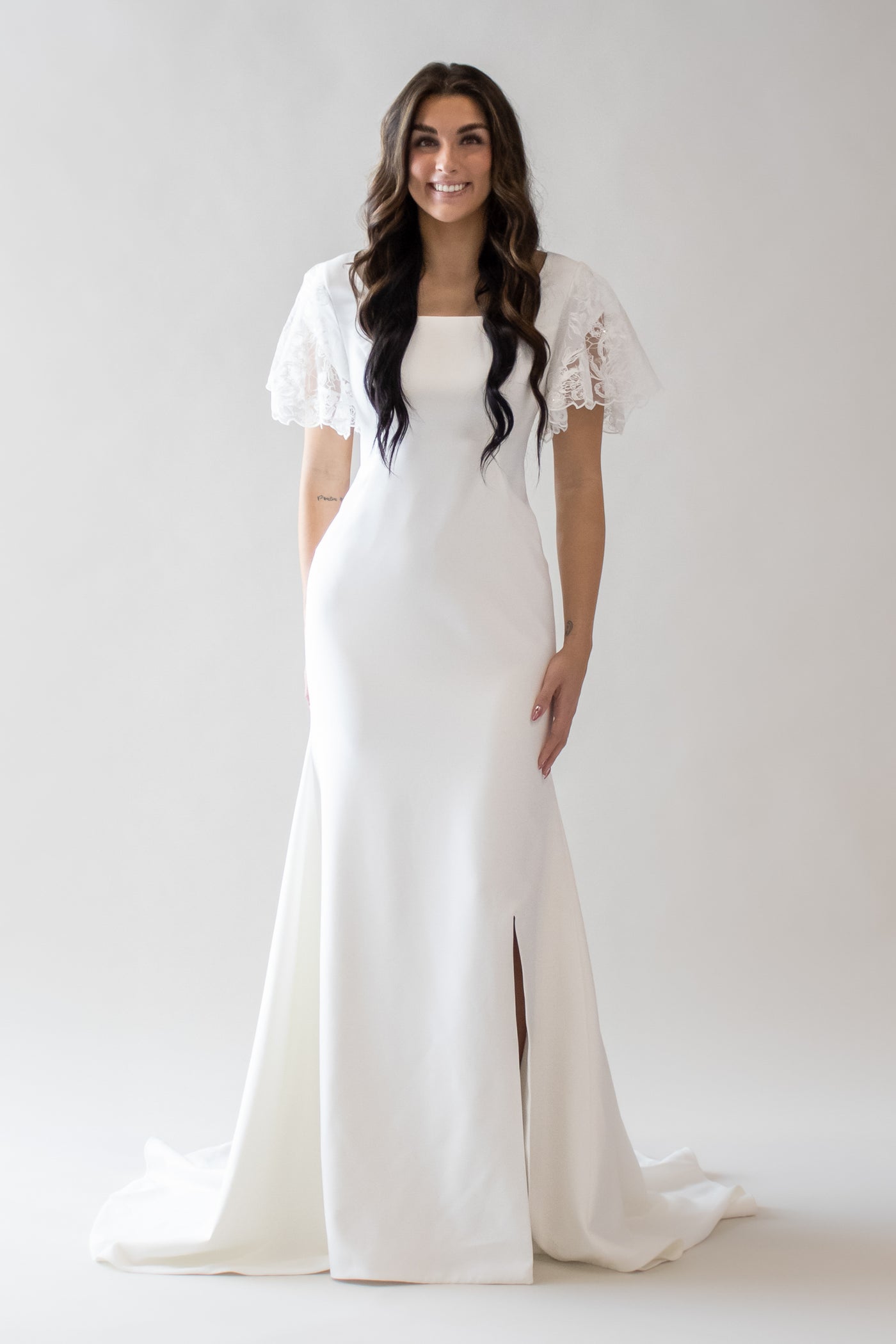 This is a modest wedding dress with a lace flutter sleeve, square neckline, a slit.