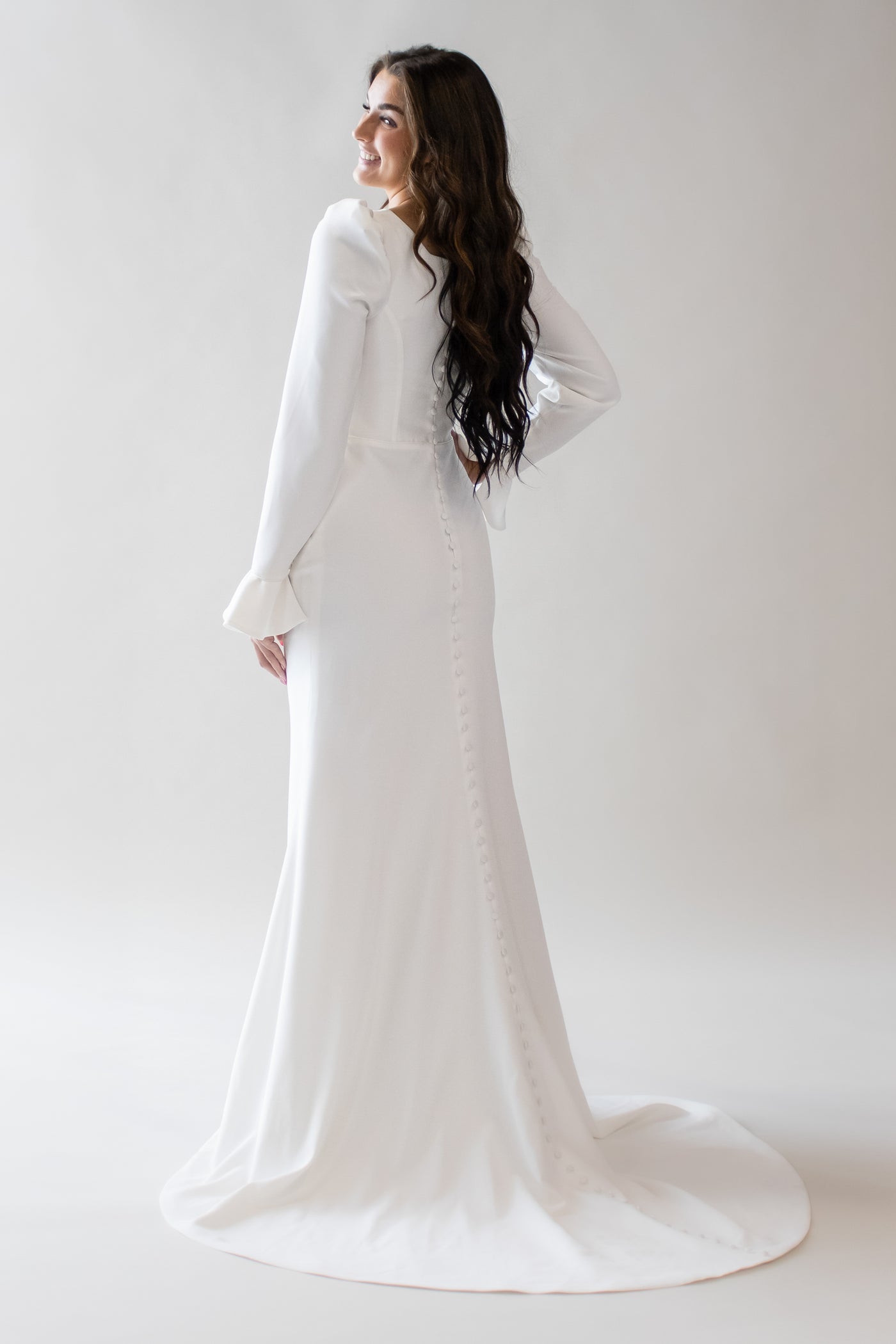 This is the back of a modest wedding gown with buttons along the entire back and a fitted silhouette.