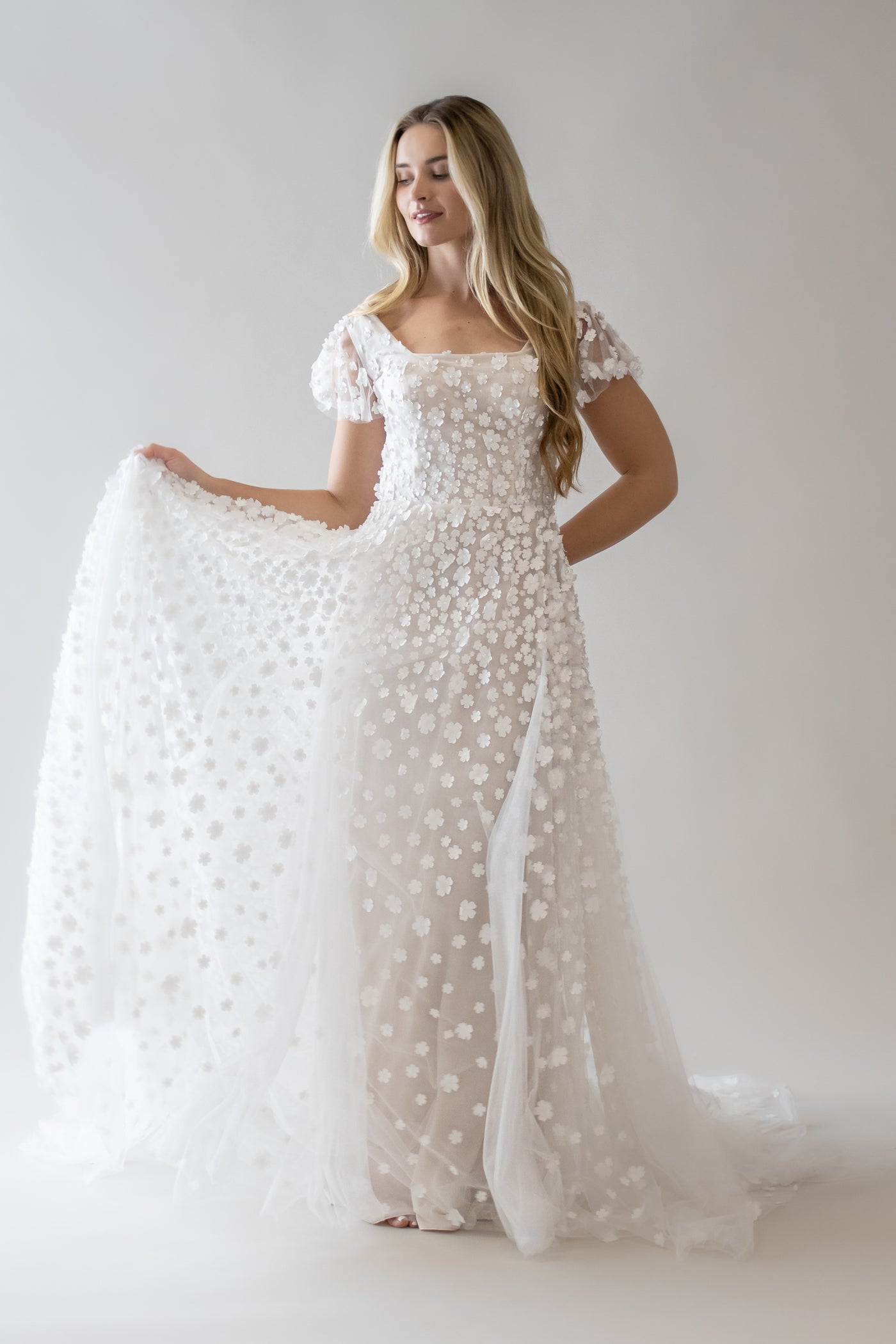 This is a modest wedding dress with  3D floral applique along the entire bodice and also features a puff sleeve.