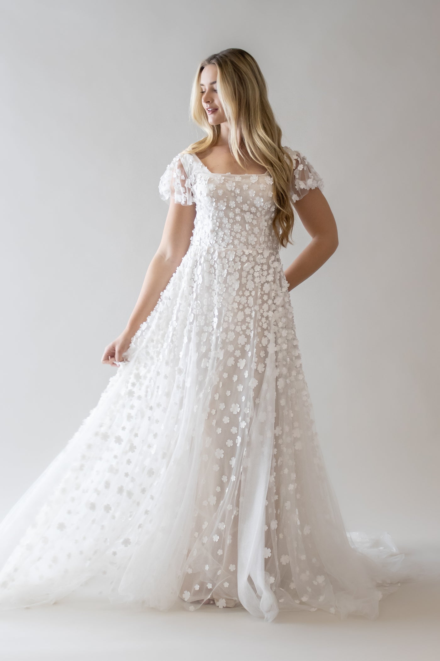 This is a modest wedding dress with an a-line silhouette a 3D floral applique.