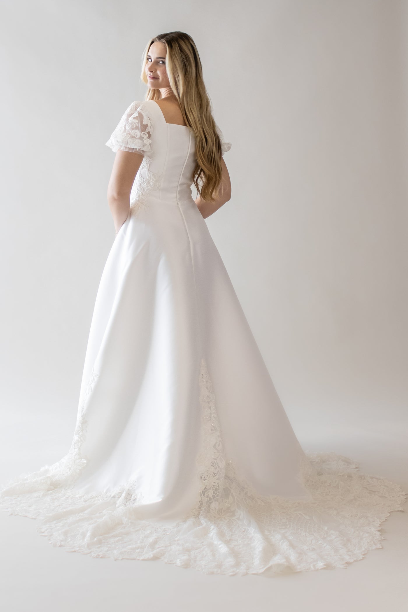 This is a modest wedding gown with a honeycomb lace train, shear laace puff sleeves, and an a-line silhouette.