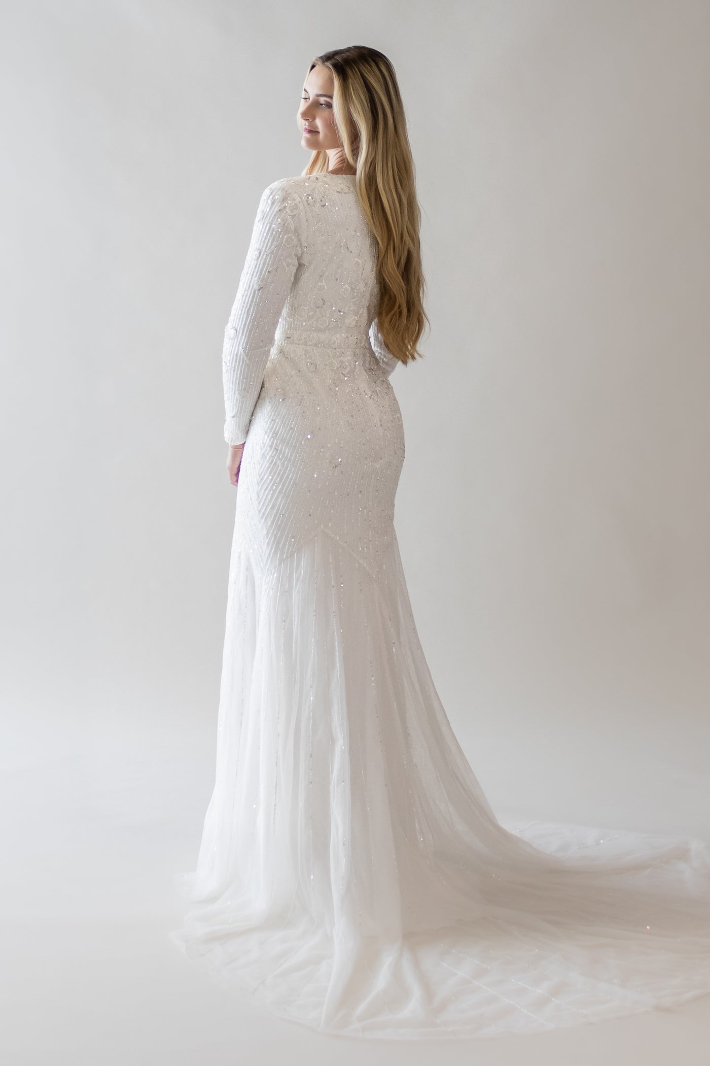 This is a modest wedding gown with a very beaded bodice, mermaid silhouette, and a simple train.