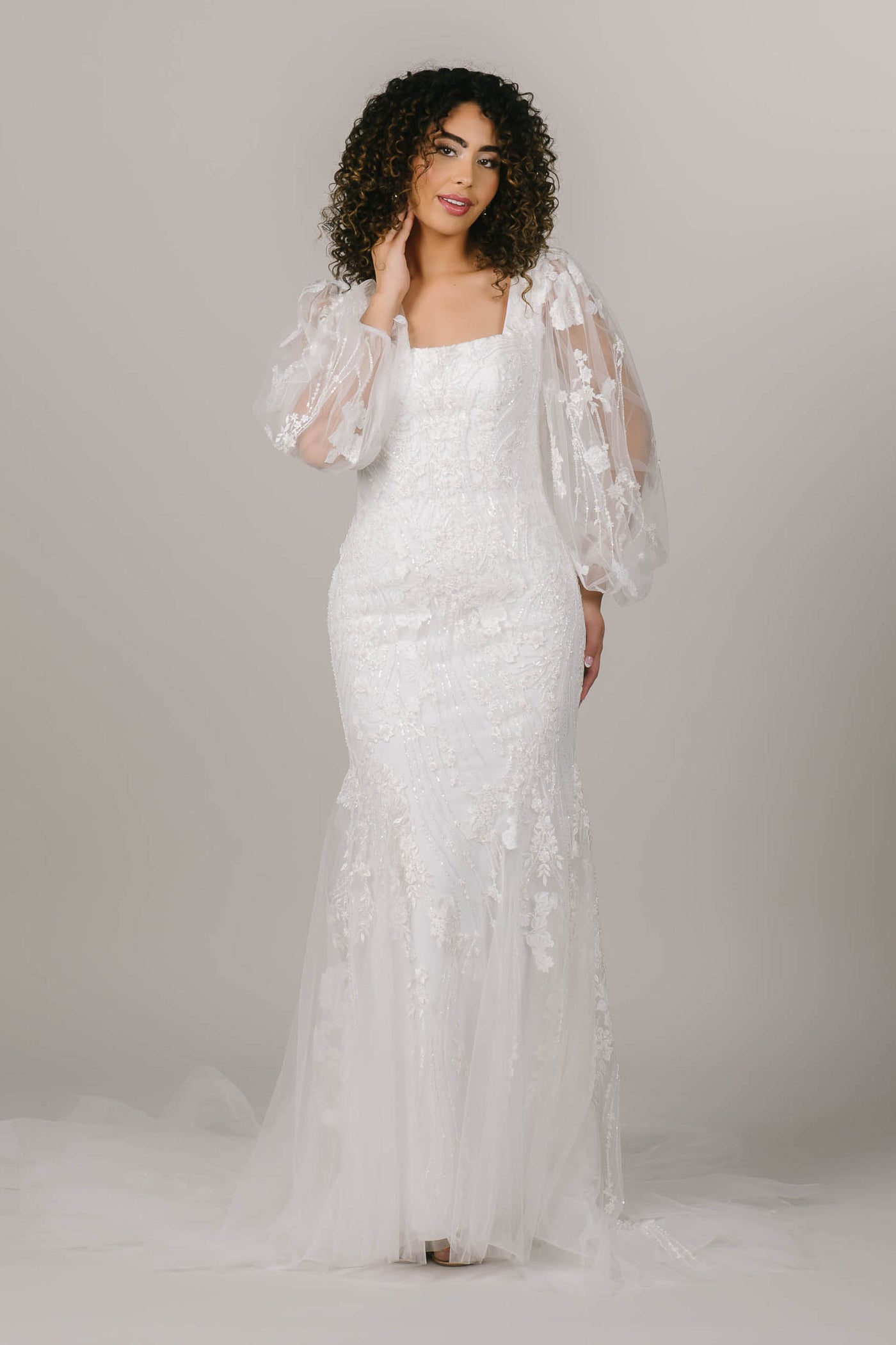 This is a front shot of a modest wedding dress with balloon lace sleeves, square neckline, and a mermaid silhouette.