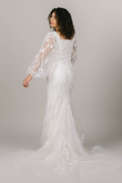 This is a back shot of a modest wedding dress with intricate beading down the back and a mermaid silhouette.