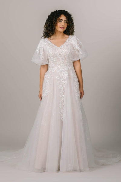This is a whimsical modest wedding dress with puff sleeves and a sparkly layer.
