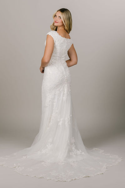 This is a back shot of a modest wedding gown with lace all along it and a fun train.