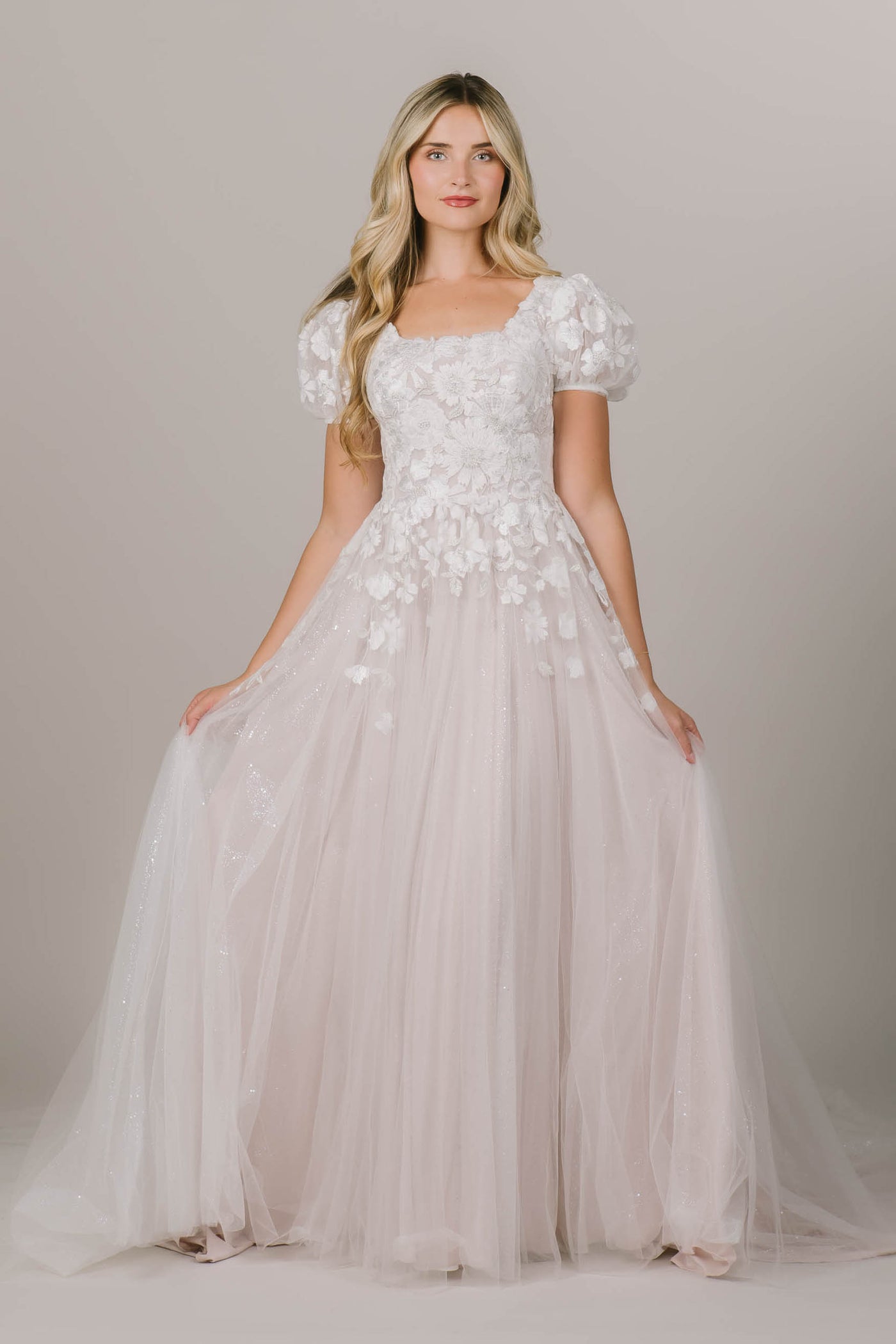 This is a modest wedding dress with puff sleeves and a a laced bodice.