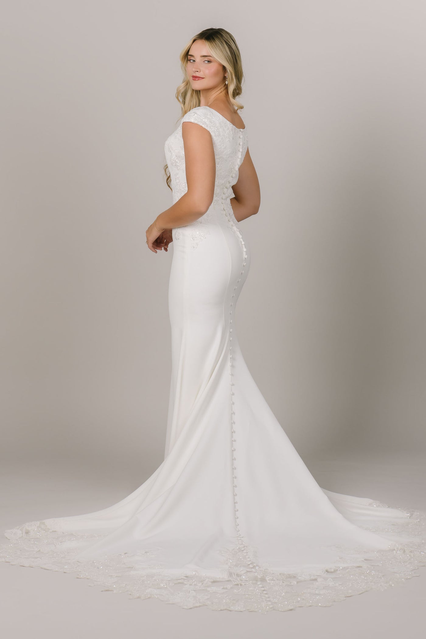 This is a simple fitted modest wedding dress with a lacy intricate train.