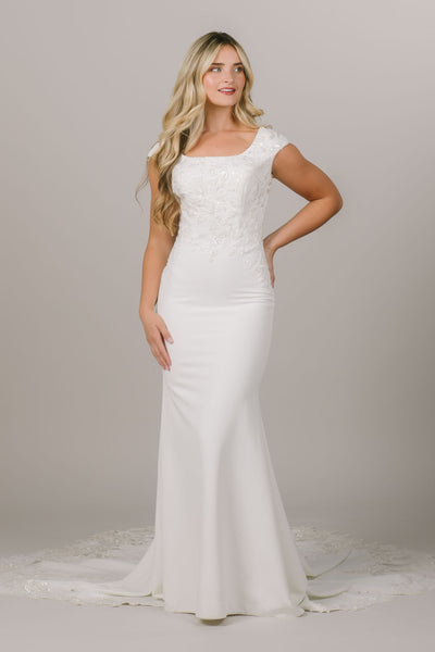 This is a modest wedding dress with a lace bodice and simple fitted silhouette.