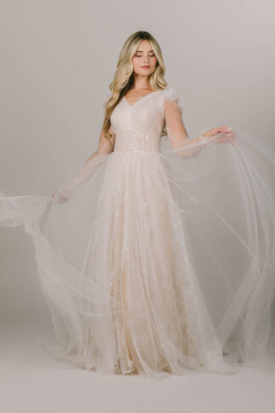 This is a modest wedding dress with a nude underlining and sparkly layers.