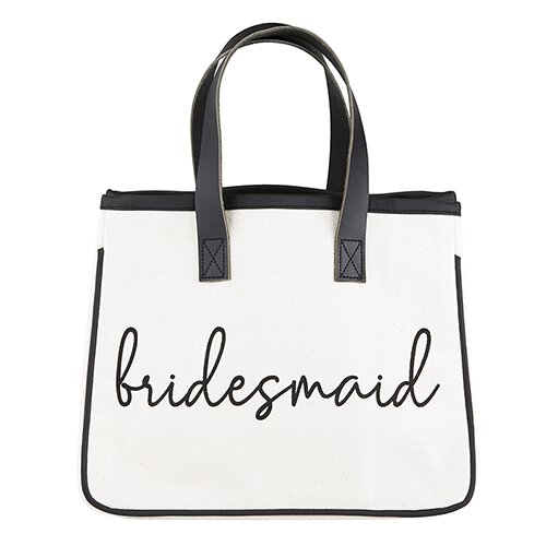 A black and white canvas tote with the word 'bridesmaid' in cursive letters on the front and a leather and hand strap.