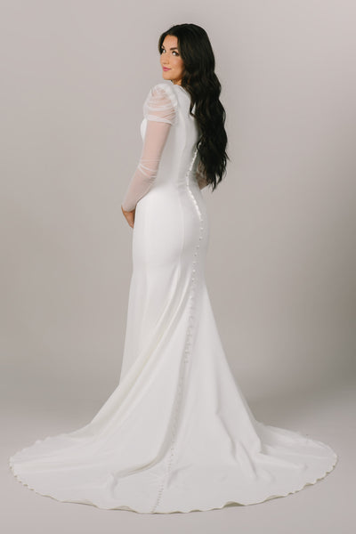 This is a back shot of a modest wedding dress with sheer sleeves and buttons all along the back.