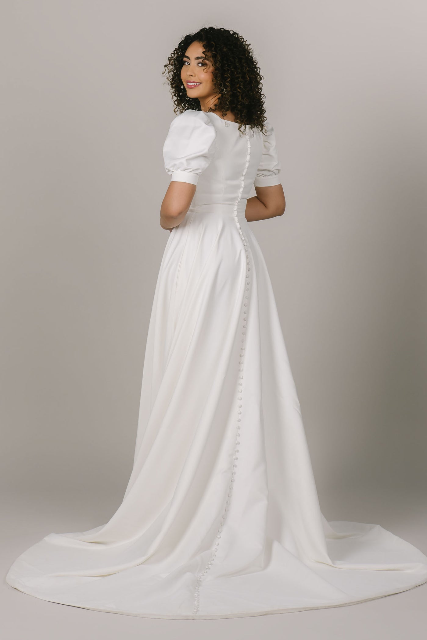 This is a back shot of a modest wedding dress with buttons along the back and a-line silhouette.