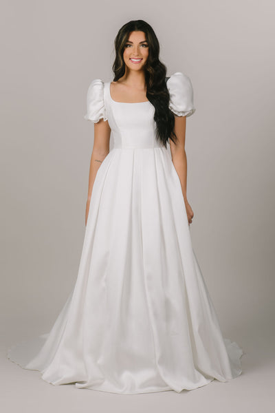 This is a front shot of a modest wedding gown with a square neckline and a ballgown silhouette.