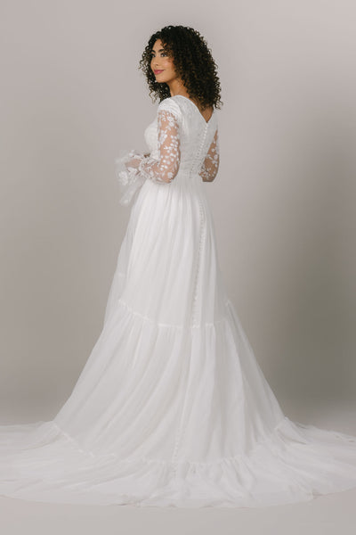 This is a modest wedding gown with buttons along the back and a tiered skirt.