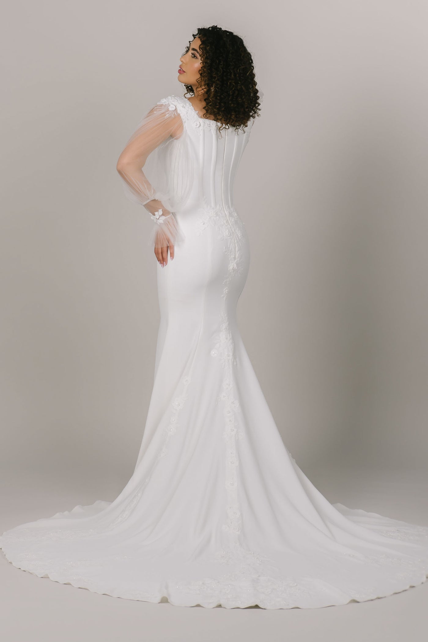 This is a back shot of a modest wedding dress with boning n the bodice and a long intricate train.