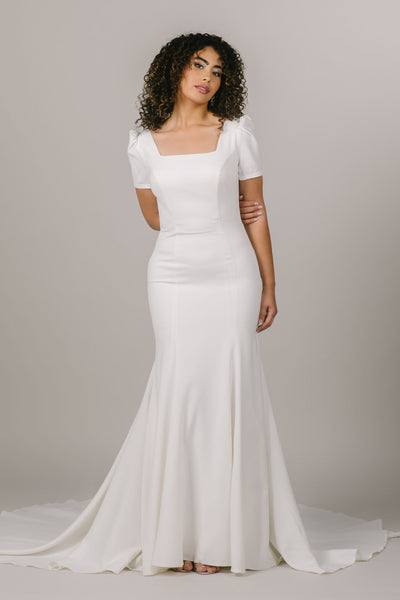 This is a front shot of a modest wedding dress with a square neckline and mermaid silhouette.