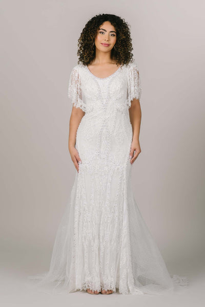 This is a front shot of a modest wedding dress with intricate beading and lace all along the dress.