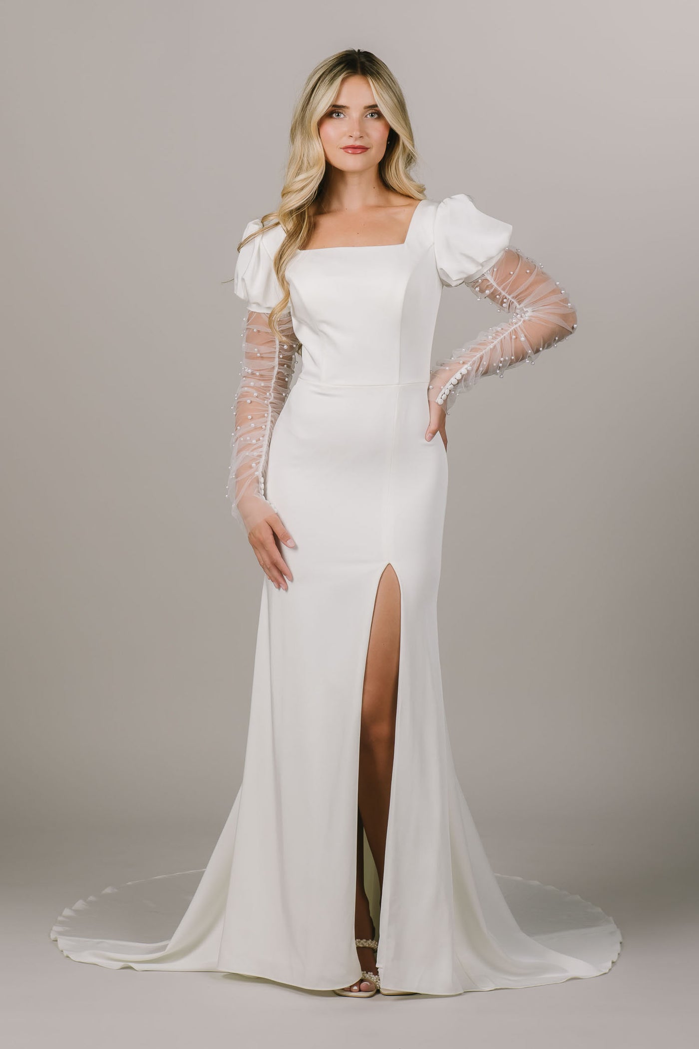 This is an alternate front shot of a modest wedding dress with a puff sleeve and detachable pearl sheer sleeves. There is also a slit in the leg leg.