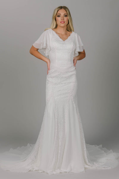 Boho modest wedding dress with sheet lace and chiffon. It has flutter sleeves and it a fitted fit. It has a v-neckline. This modest wedding dress frames the body so beautifully!