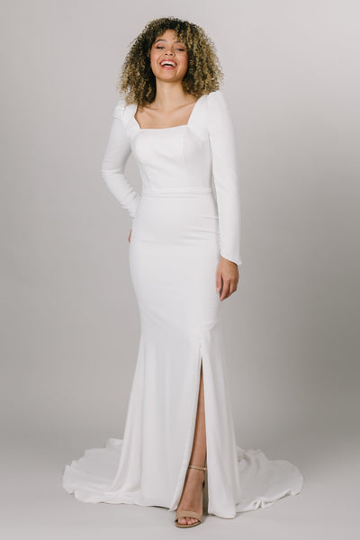 Front view of modest wedding dress with long puffed sleeves. This dress is fitted with a knee high slit and a square neck line. 