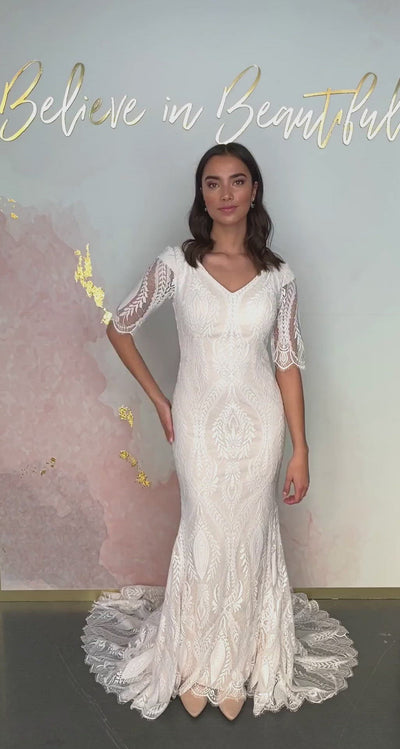A video featuring our Ame wedding dress and its flattering sheath fit, with a unique lace pattern and sheer lace sleeves.