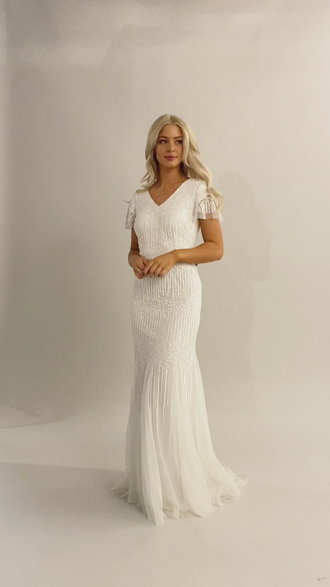 Video of modest wedding dress with flutter sleeves and v-neckline. It is a fitted dress with sequin beading. This Moments Made Bridal dress is stunning on any body type.