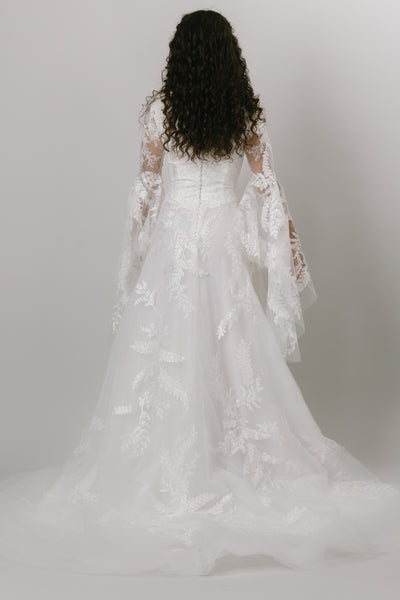 the back of a-line modest wedding dress, with bell sleeves and appliques.  