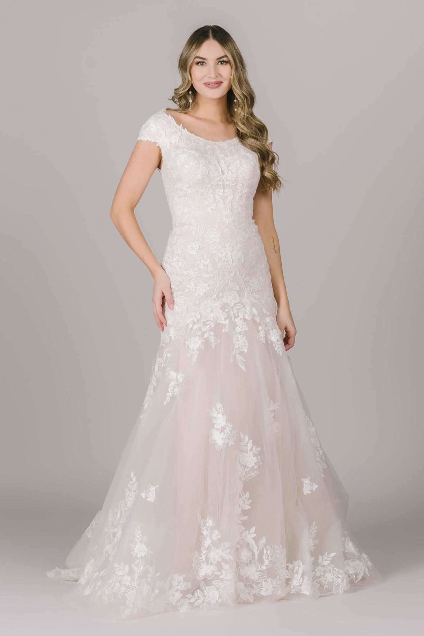 Another angle of a modest wedding dress with a fitted silhouette, cap sleeves, and a wide scoop neckline.