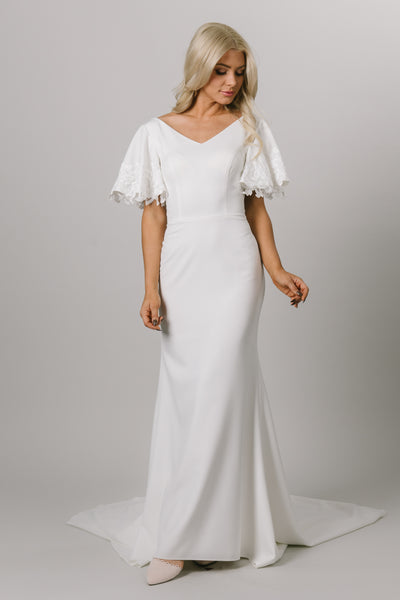 Sleek and modern flutter sleeve gown. The flutter sleeves have lace on the edge. This modest wedding dress is fitted and has a v-neckline. Moments Made Bridal loves this elegant modest wedding dress.