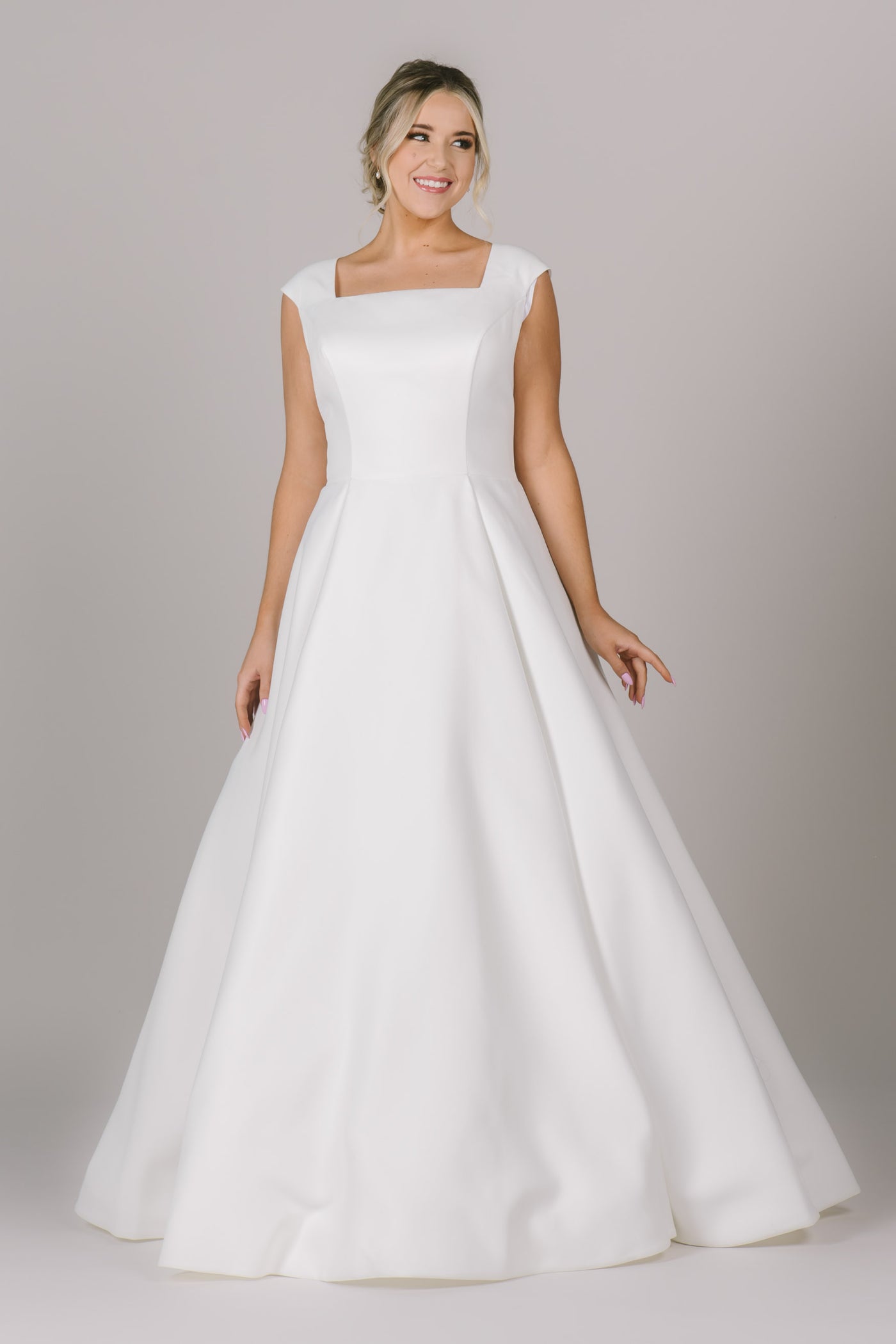 Another shot of a simply and classy modest wedding dress in Bluffdale, UT is made with a beautiful crepe material and is paired with a square neck, cap sleeves, and pockets!