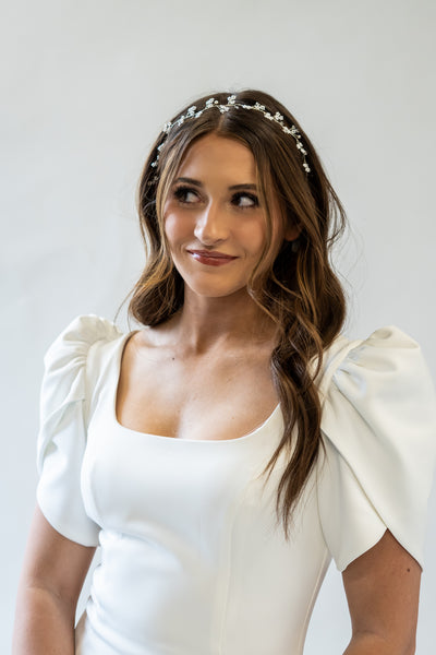 A portrait shot of a simple and delicate headpiece with pearl floral accents and a gold band.