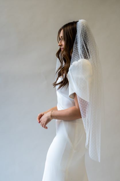 A side profile portrait shot of a fingertip length swiss dot bridal veil. The perfect accessory to add to a simple wedding dress. 