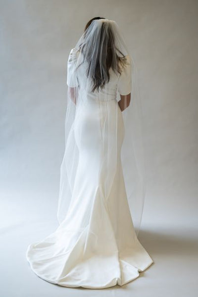 A back view full body shot of a chapel length simple bridal veil. It barely brushes the floor and is perfect to add an added elegance to any wedding gown.