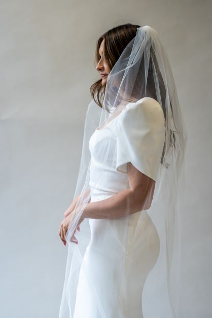 A side profile portrait shot of a chapel length simple bridal veil draping around a bride. The perfect veil to add an elegance to any bridal look.