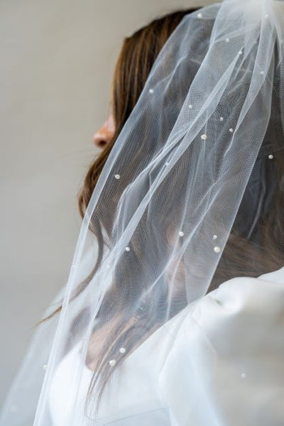 A close up side angle of a simple, scattered pearl veil perfect for completing any bridal look.