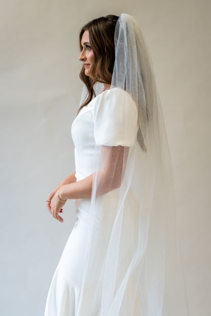 A side profile portrait shot of a simple cathedral length bridal veil with sparkle throughout.