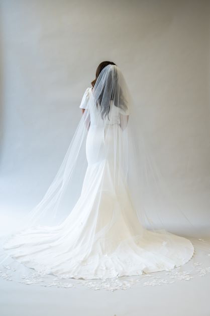 A full body shot of a cathedral length bridal veil with lace lining the bottom edge. It drapes beautifully around the train of the wedding gown.