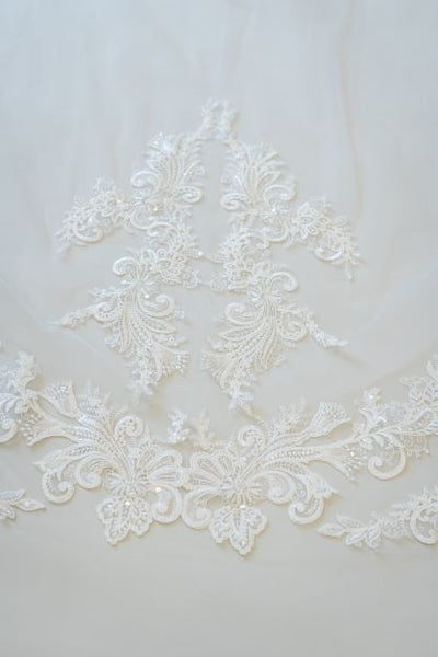 A close up shot of lace on a cathedral length bridal veil. The lace is elegant and contains a small amount of sparkle from beading.
