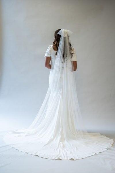 A full length shot of a soft cathedral bow veil with pearls, spread out behind the long train of a simple classy wedding gown. 